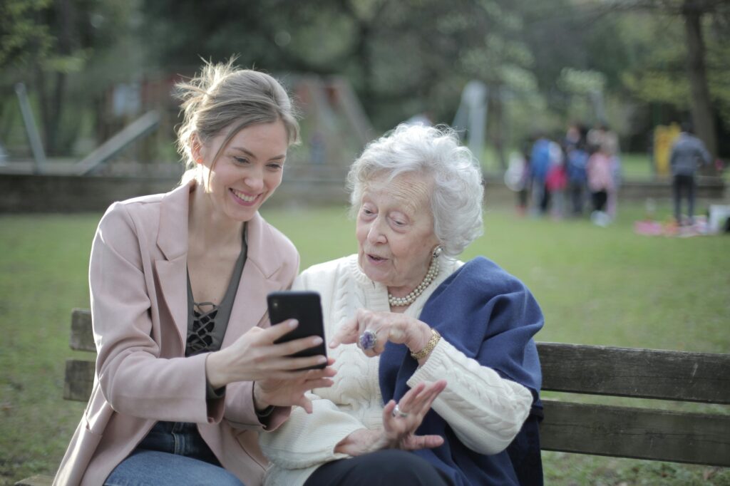 A mother and daughter are on a bench in a park