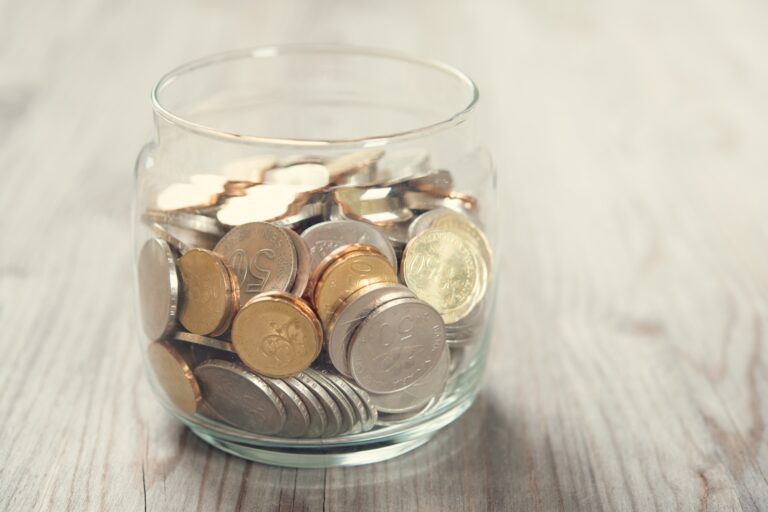 Coins in a glass jar in the concept of saving money for moving to Coulsdon.