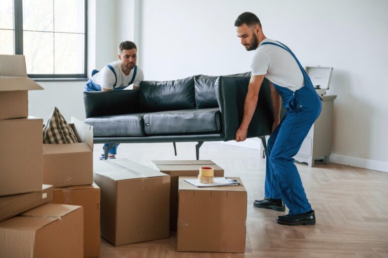 Two movers lifting a long sofa in the concept of 'How Do Home Removals Services Work in Coulsdon'.